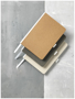 medium size cardboard notebooks in brown, charcoal and white with white fabric spine, ribbon and elastic pen loop
