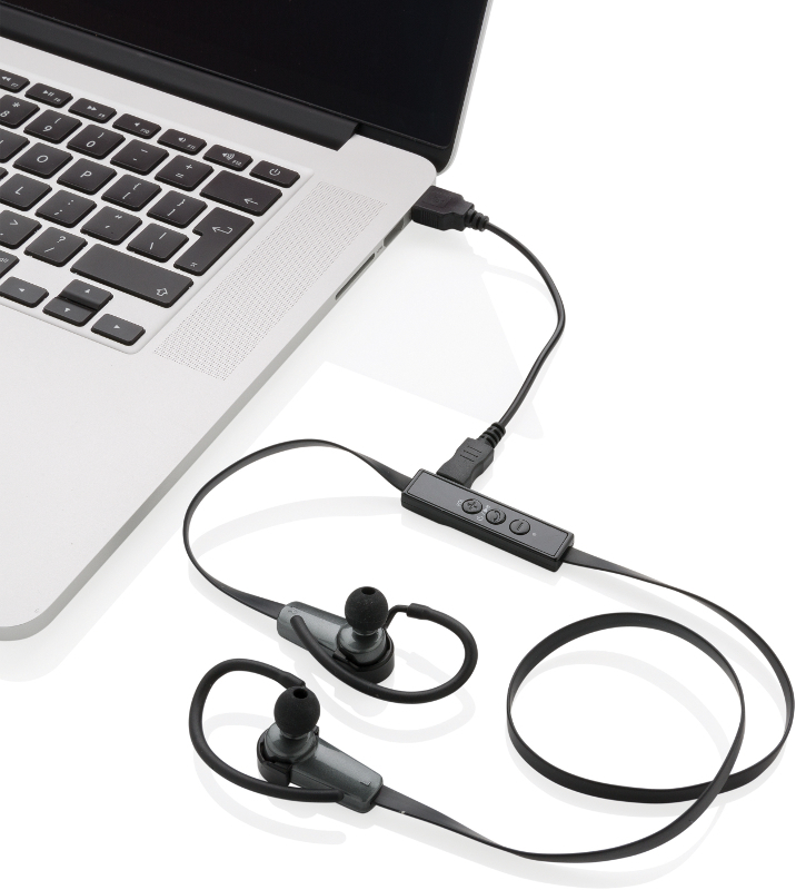 Bluetooth earbuds plugged into charge on laptop