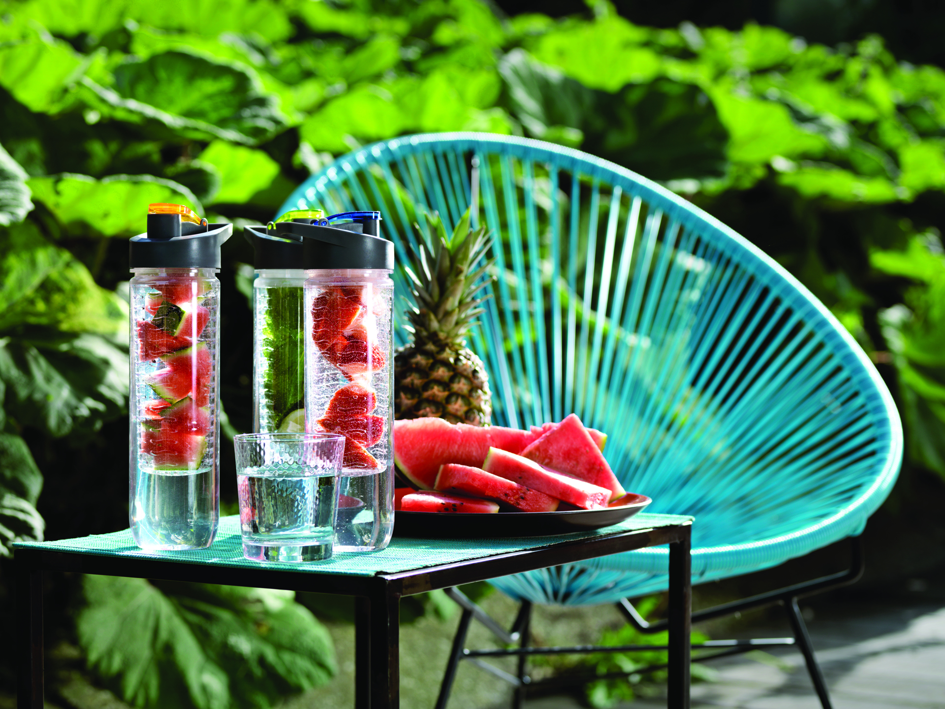 outdoor scene of water bottles with fruit infusers and black lids