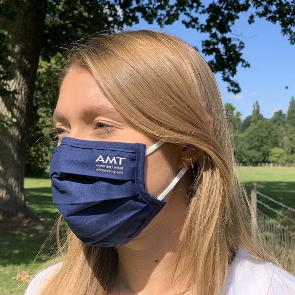 person wearing blue pleated face mask with branding to one side