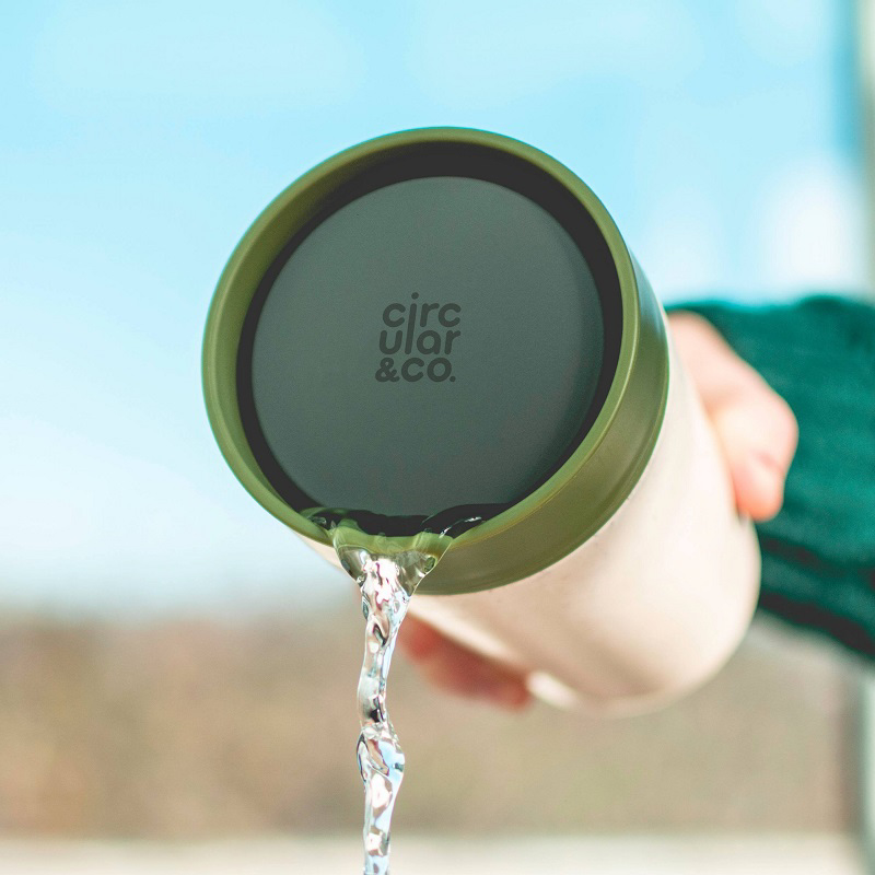 circular co cup with green lid being poured