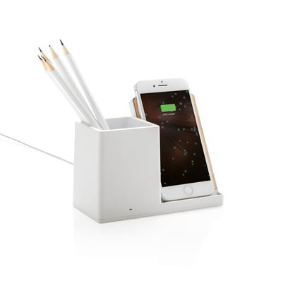 A white plastic wireless charger with a pencil pot on the left holding pencils and a phone on the stand