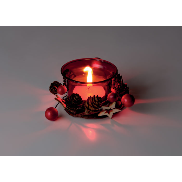 A red christmas candle that has been lit, with ornaments surrounding the base
