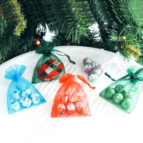 four netted bags containing 6 circular chocolates. The bags are green, blue, white, red, and dark green.