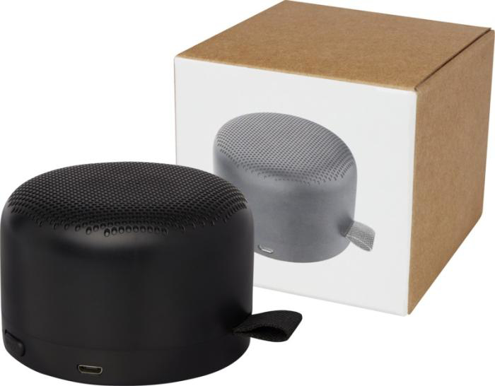 A black circular bluetooth speaker and its' packaging