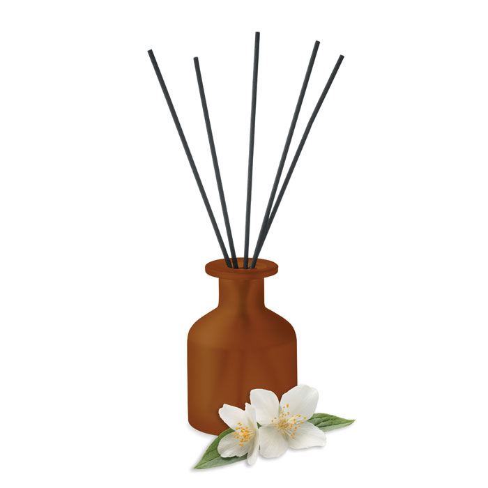 red fragrance stick diffuser with flower of scent next to it 