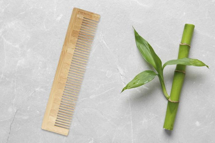 wooden comb light brown in colour next to a stick of bamboo