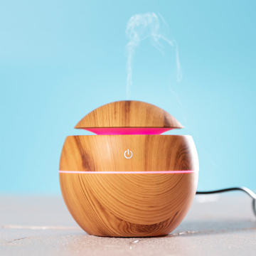 A brown humidifer / diffuser, with steam coming out the top and a pink led light