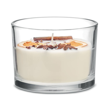 A cream coloured candle with orange fruits and leaves on top in a transparent glass jar