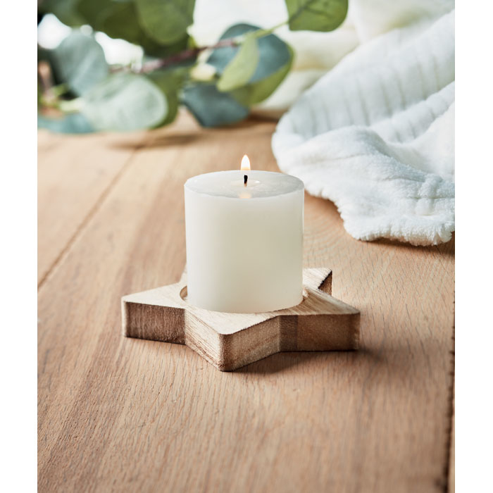 A white candle in a brown wooden base in the shape of a star, on display on a table