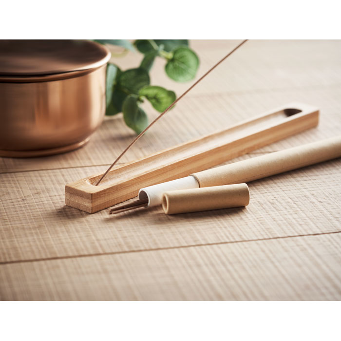 a light brown rectangular bamboo holder with incense sticks and its packaging on display