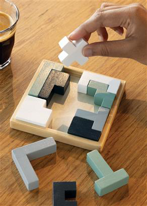 Wooden puzzle with green, white, black and grey pieces on display