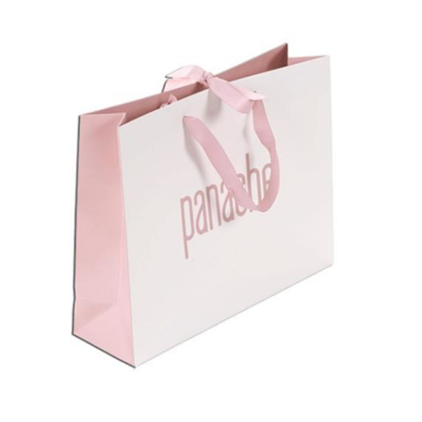 White paper bag with pink sides and pink ribbon and handle and pink logo