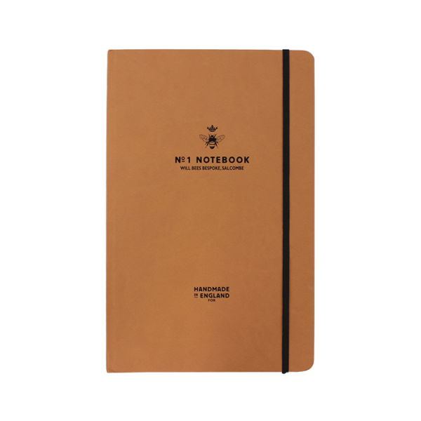 	Will Bees crown notebook in tan with black elastic closure strap and black embossed logo